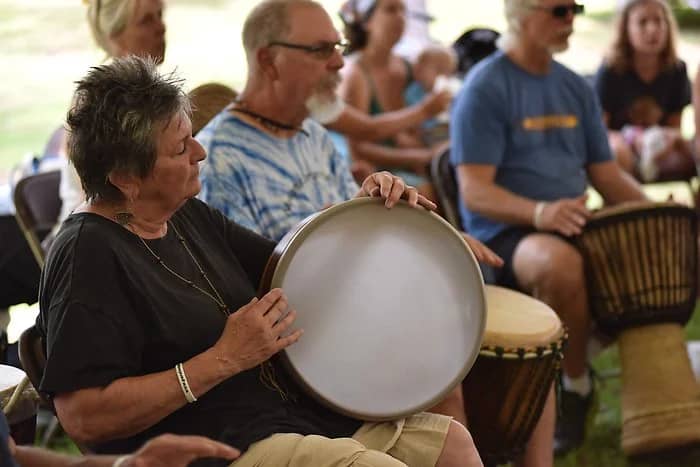 Participants in a drum circle at a festival, creating rhythmic music and building community connections.